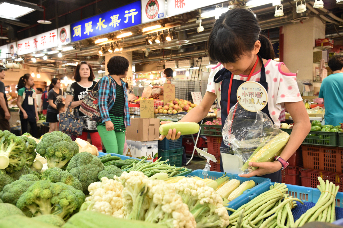 圖說3：小小市場達人學習認識蔬菜種類，協助攤商老闆進行整貨補貨。
